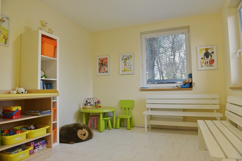 Světlá čekárna s lavicemi, hračkami a dětskými kresbami na stěnách